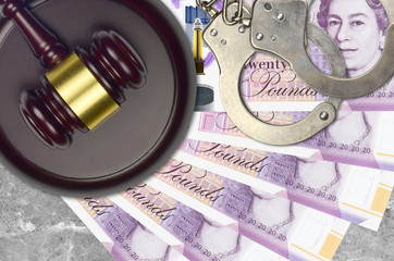 20 British pounds bills and judge hammer with police handcuffs on court desk. Concept of judicial...