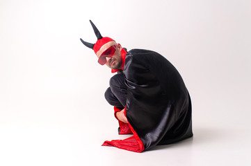Strange devilish man in sunglasses and black red halloween costume posing over white background.