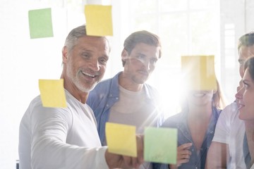 Business people meeting at office and use post it notes to share idea. Brainstorming concept. Sticky note on glass wall.