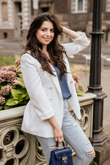 Smiling attractive woman wearing white fashion jacket and jeans look in camera