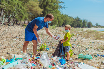 Volunteers in blue face mask. Father, son pick up garbage which pollute beach near lazur sea....