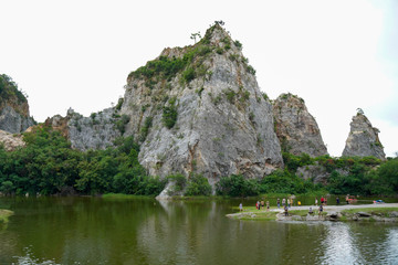 Beautiful range of rocks mountain with many tourist and sightseeing around still pond or lake at Kuao Hin Ngu public park in Ratchaburi province, Thailand