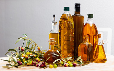 Organic olive oil in bottles garnished with ripe olives on wooden background