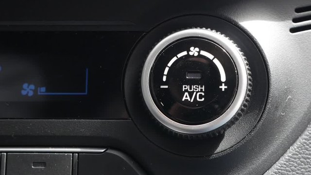 Close-up of pushing a button to turn off the air conditioner in a car. The mans hand turns the button