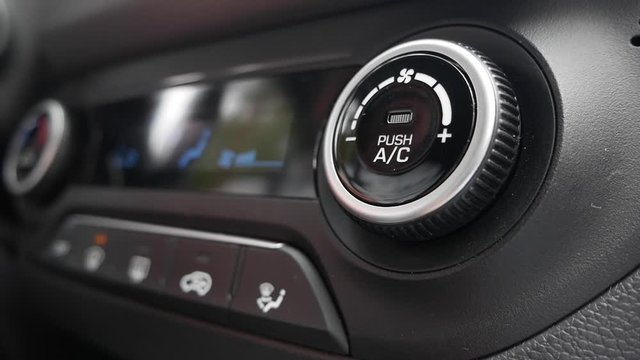 Close-up of pushing a button to turn off the air conditioner in a car. The mans hand turns the button