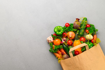 Paper bag of different vegetables on a gray background. Top view, copy space. Bag food concept.