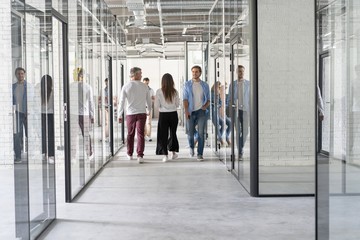On the way to business meeting. Full length of young modern people in smart casual wear having a discussion while walking through the office