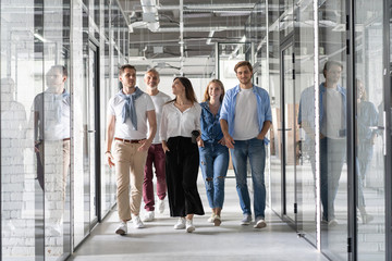 Obraz premium On the way to business meeting. Full length of young modern people in smart casual wear having a discussion while walking through the office