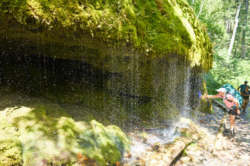 Waterfall flowing over a mossy rock with cave behind in the Canyon 