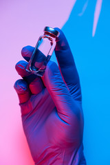 The doctor holds an ampoule with a vaccine. Hand in medical glove with the glass ampoule..Concept of danger or the need for vaccination.