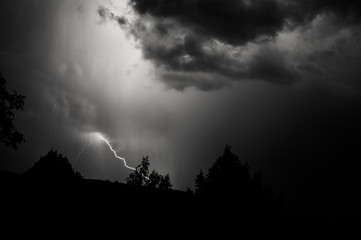 Fototapeta premium Lightning storm at night over dark landscape