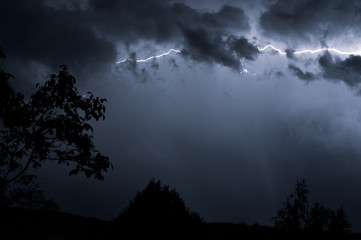 Lightning storm at night over dark landscape