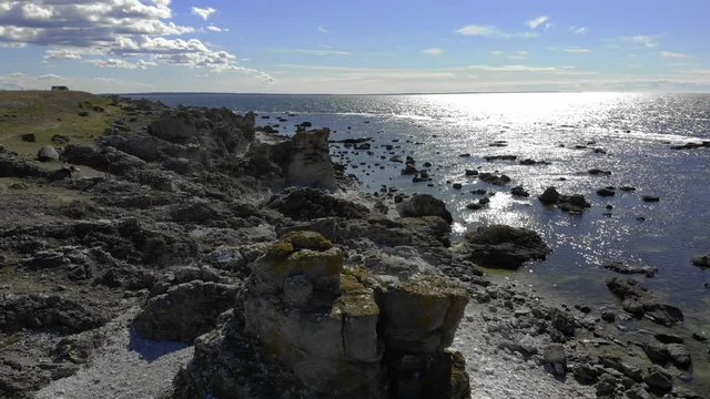 Aerial view around a rauk field, full of limestone rock formations, on the coast of F&auml;r&ouml; island, warm, summer day, in Gotland, Sweden - orbit, drone shot 