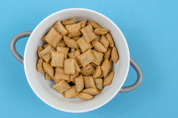 Bowl with sweet corn pads with chocolate inside on a blue background, copy space, top view