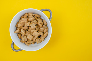 Bowl with sweet corn pads with chocolate inside on a yellow background, copy space, top view