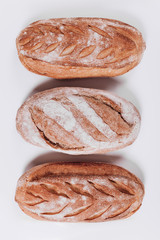 Bakery bread - fresh rustic crusty loaves of bread and baguette on white background.  (top view, flat lay).