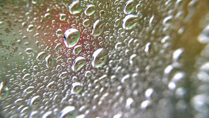 Heavy rainfall / raindrops on a window looking out to a mostly green garden