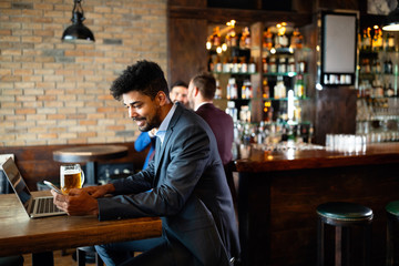 Handsome young business man, blogger or remote working with laptop in bar
