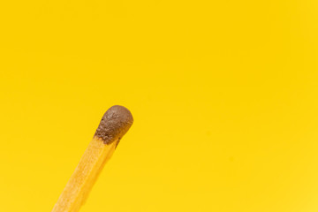 Match with a brown head on a yellow background with copy space, macrophotography