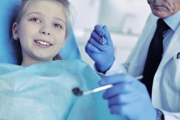 Naklejka premium Little girl sitting in the dentists office