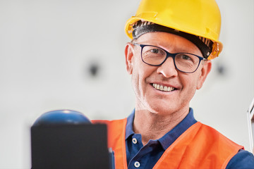 Portrait of a engineer working in factory wearing protective glasses and headphones 