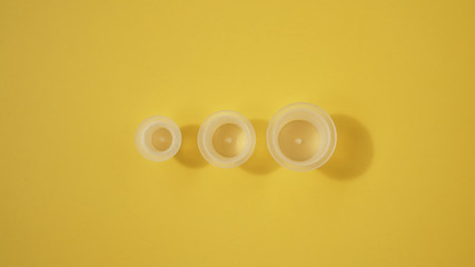 Three ink plastic caps on yellow background - tattoo concept