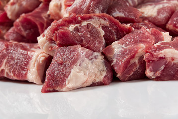 Chopped raw pork meat on white glass close-up.