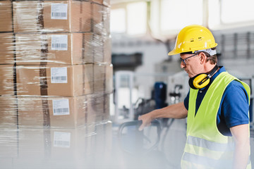 
Warehouse worker using forklift and sorting boxes