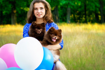 Beautiful girl with balloons and Pomeranians in nature.