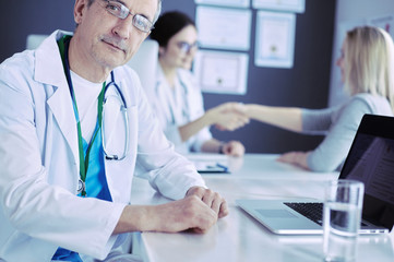 Doctor and patient discussing something while sitting at the table . Medicine and health care concept