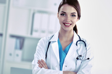 Portrait of young woman doctor with white coat standing in hospital