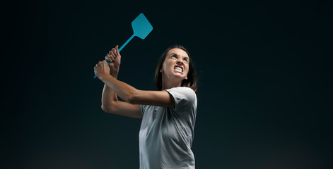 Angry woman killing mosquitoes with a fly swatter