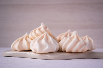 Fototapeta na wymiar Delicious meringues on ceramic board. Homemade meringue cookies.