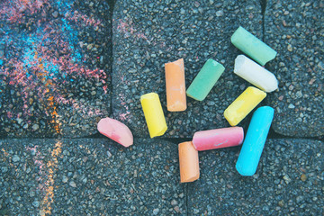 Blurred image Colorful pastel sidewalk chalk on dark asphalt background. children's crayons on the asphalt close up. The concept of development of children's creativity. selective focus. No focus
