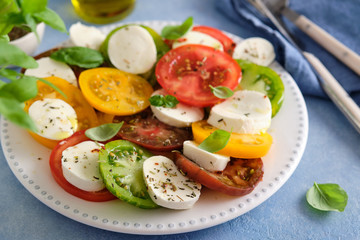 Caprese salad with mozzarella, colored tomatoes and fresh basil.
