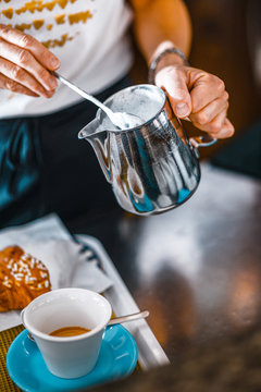 female italian barista preparing espresso coffee , cappuccino and whole milk for cappuccino in a bar in the morning with italian design coffee machine