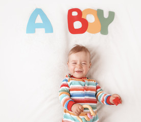 Baby boy lying on the blanket with letters above