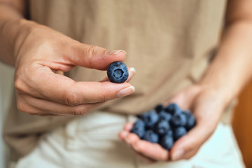 Blueberries in women hands. Natural organic berries. Fresh beautiful blueberry close up. Delicious summer wild berry. Berries for dessert. Healthy lifestyle, vegetarian sweet snack