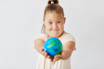 Portrait of down syndrome girl holding model of the Earth planet and looking at camera isolated on white background