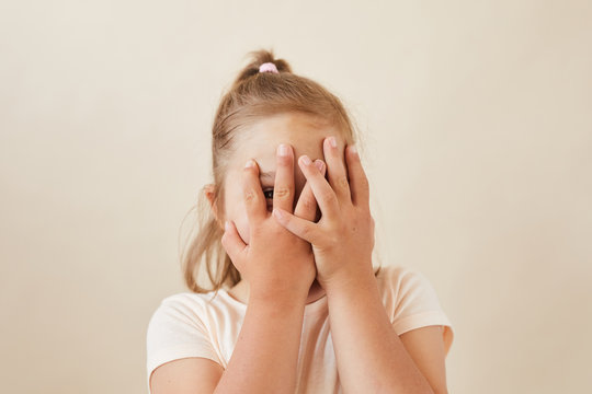 Portrait Of Little Girl Hiding Her Face With Hands She Playing Hide And Seek Isolated On White Background