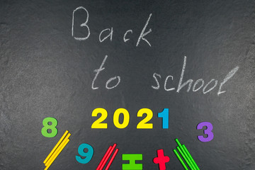 2021 Multicolored colorful numbers, counting sticks, math signs on a chalkboard. Back to school. Concepts. School supplies on a chalkboard. View from above.