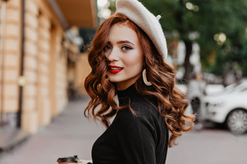 Gorgeous white girl with long wavy hair chilling in autumn day. Outdoor portrait of interested...