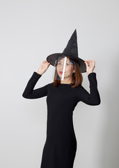 Woman wearing witch costume and mask face shield for Halloween