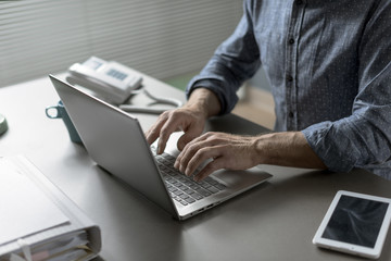 Businessman sitting at desk and typing on a laptop