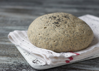 Yeast dough from rye flour with poppy for baking bread on wooden table, selective focus