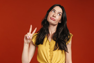 Image of young displeased woman showing peace sign and looking aside