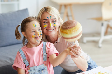 Smiling mother showing her daughter with down syndrome the model of the planet