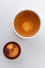 Tasse de café espresso et sa capsule vue de dessus