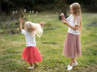Two sisters blowing soap bubbles and having fun