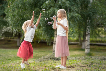 Two sisters blowing soap bubbles and having fun